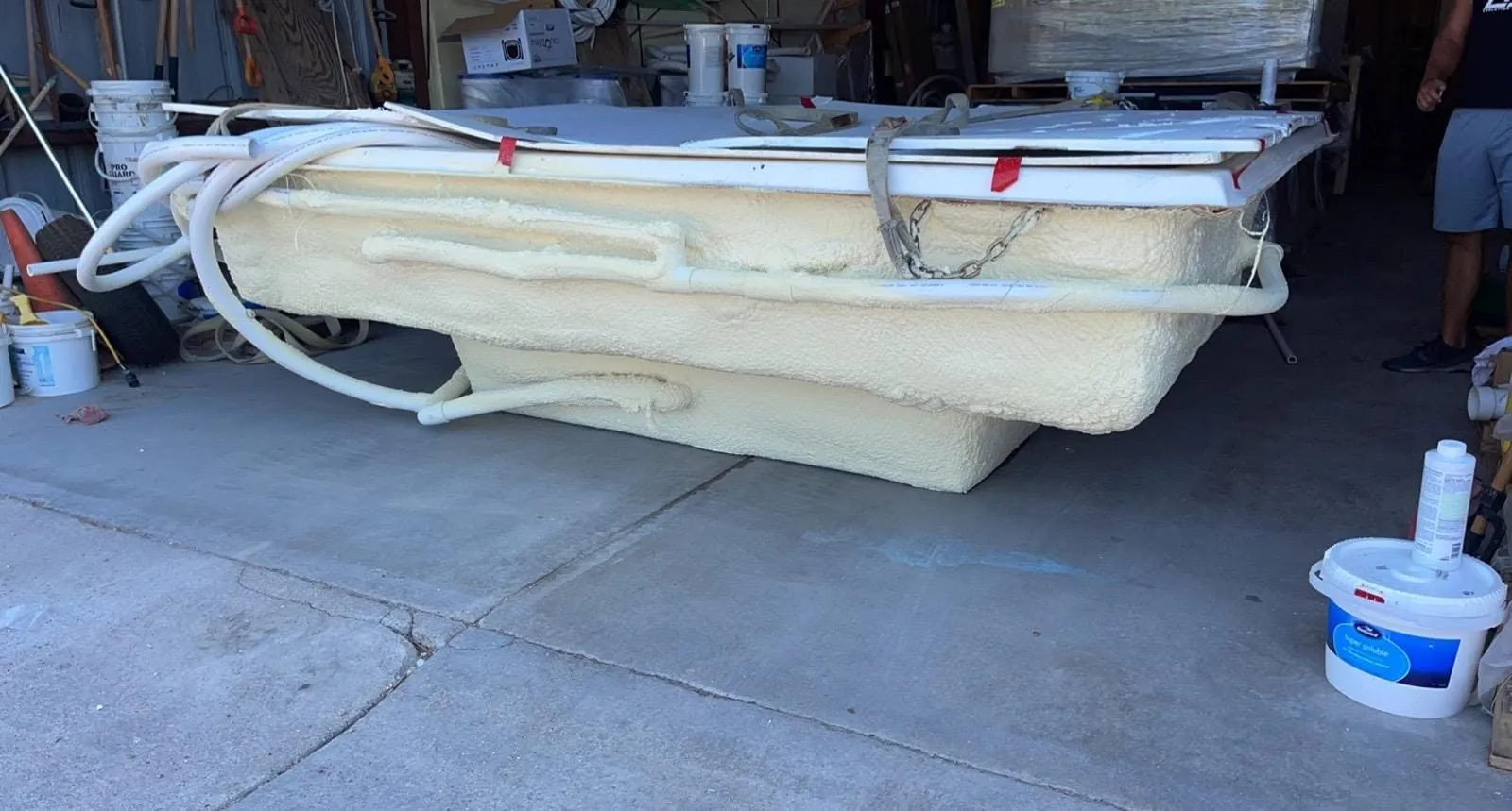Spa shell thickly coated in yellow closed-cell spray foam with the plumbing lines foamed in